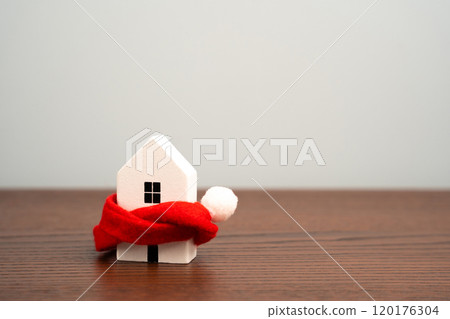 Wooden house and red scarf. The concept of warming of houses and apartments. Heating system. Energy saving. Increase energy efficiency at home. Copy space 120176304