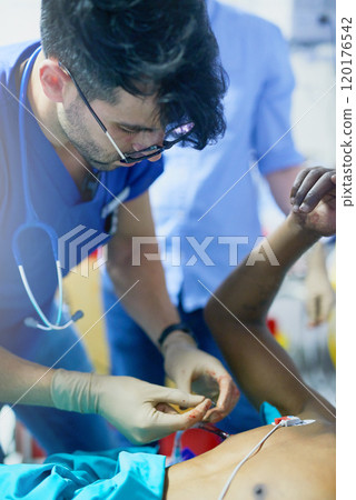 Focus is a critical skill required in trauma. Shot of a doctor inserting a tube into a patients chest in an emergency room. Focus is a critical skill required in trauma. Shot of a doctor inserting a tube into a patients chest in an emergency room. 120176542