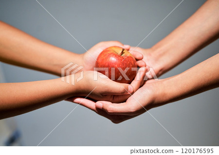An apple a day...Studio shot of an unrecognizable woman giving a child an apple. 120176595