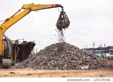 Industrial re-purposing. Cropped shot of an excavator sorting through a pile of scrap metal. Industrial re-purposing. Cropped shot of an excavator sorting through a pile of scrap metal. 120176596