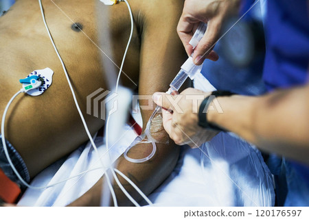 Drug administration via an iv drip. Cropped shot of a doctor inserting an iv drip into a patients arm in an emergency room. 120176597