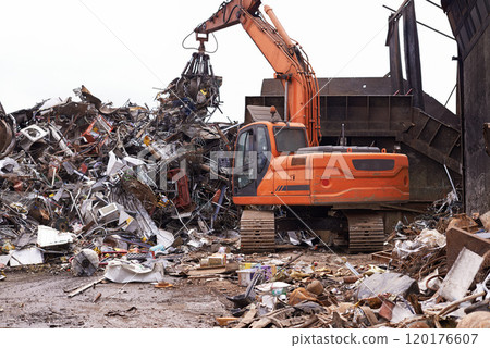 The scrapyard. Cropped shot of an excavator sorting through a pile of scrap metal. The scrapyard. Cropped shot of an excavator sorting through a pile of scrap metal. 120176607