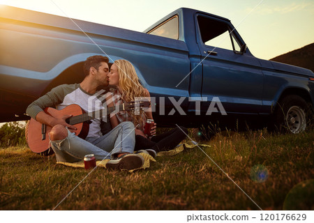 Music inspired by love. Shot of a young man playing guitar for his girlfriend on a roadtrip. Music inspired by love. Shot of a young man playing guitar for his girlfriend on a roadtrip. 120176629