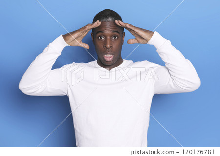 Surprised man in white sweater with hands on head 120176781
