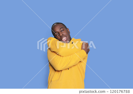 Happy man hugging himself in a yellow hoodie 120176788