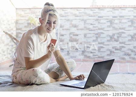 Woman online shopping with laptop and credit card at home. 120176924