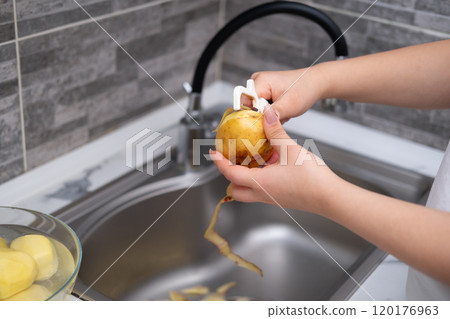 Woman's hands peeling potatoes close up Woman's hands peeling potatoes close up 120176963