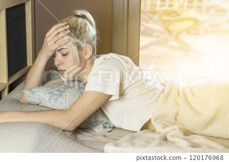 Woman lying on bed, holding head, looking pensive and tired. Woman lying on bed, holding head, looking pensive and tired. 120176968