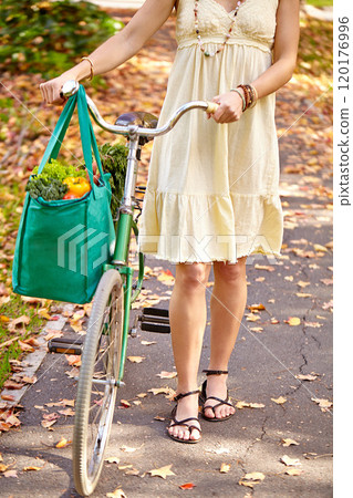 Looks like shes been by the grocery store. Cropped shot of a young woman walking home from the grocery store with her bicycle. 120176996