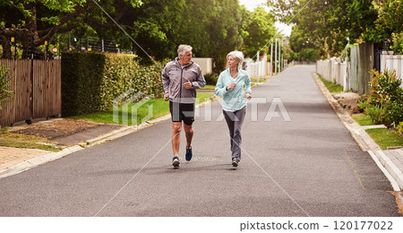 Try and keep up. Shot of a cheerful senior couple having a jog together outside in a suburb. 120177022