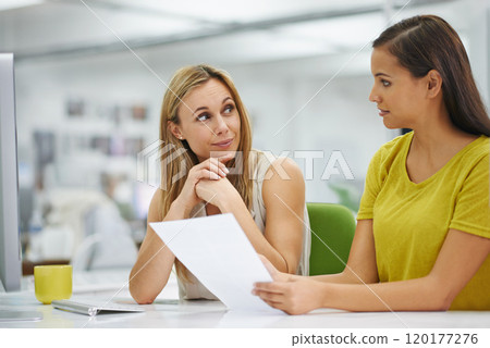 Im listening to what you are suggesting. Two attractive female colleagues going over some documents at work. 120177276