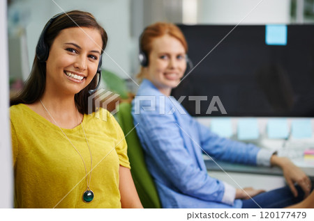 Were here to make a difference. Shot of two attractive female colleagues with headsets at the office. 120177479