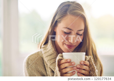 Having a cup of sereni-tea. Shot of a young woman enjoying a warm beverage at home. 120177634