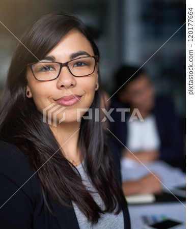 Shes an asset to the company. Portrait of a smiling young businesswoman in an office with colleagues in the background. 120177664