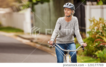 Where should I go now. Cropped shot of a cheerful senior woman riding on a bicycle by herself outside in a suburb. 120177789