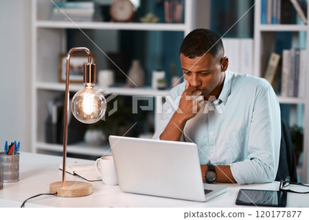 Success involves a lot of late nights and thorough thinking. Shot of a handsome young businessman working on his laptop during a late night shift at work. 120177877