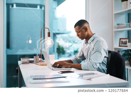 Hes in his productive zone. Shot of a handsome young businessman working on his laptop during a late night shift at work. 120177884