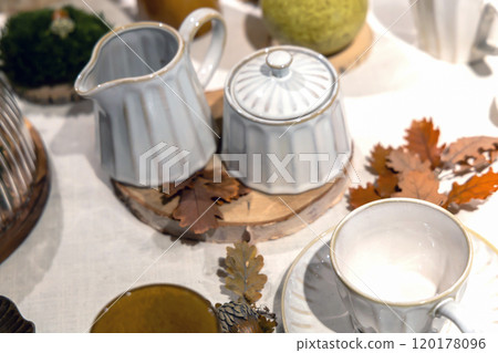 Autumn table setting with white cups and yellow oak leaves on the table Autumn table setting with white cups and yellow oak leaves on the table 120178096