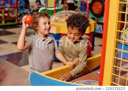 Friendly boys playing by slot machine 120178123