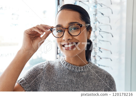Loving the look of these. Shot of a young woman buying a new pair of glasses at an optometrist store. 120178216