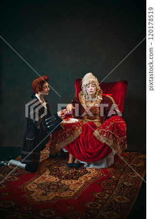 Humorous scene with elderly woman and young man, Medieval empress sitting in chair with young male servant doing painting her nails 120178519