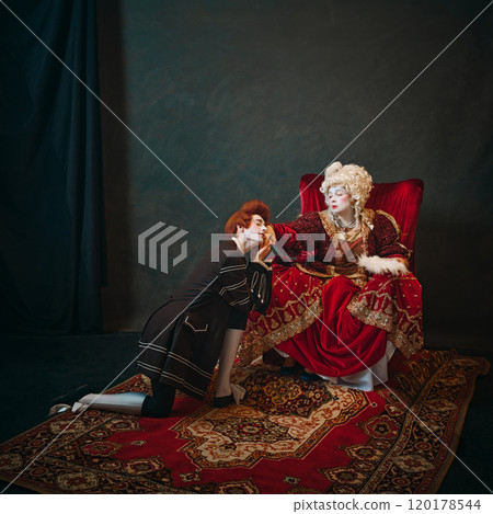 Empress, adorned in opulent gown, offers her hand in greeting to her kneeling favorite, embodying intimate moment in royal court. Empress, adorned in opulent gown, offers her hand in greeting to her kneeling favorite, embodying intimate moment in royal court. 120178544