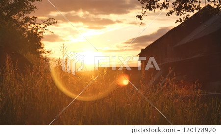 Serene rural sunset scene with a grassy field and barn bathed in warm sunlight Serene rural sunset scene with a grassy field and barn bathed in warm sunlight 120178920