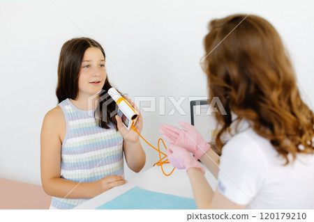 Girl testing breathing function by spirometry in doctors office. Diagnosis of respiratory function in pulmonary disease 120179210