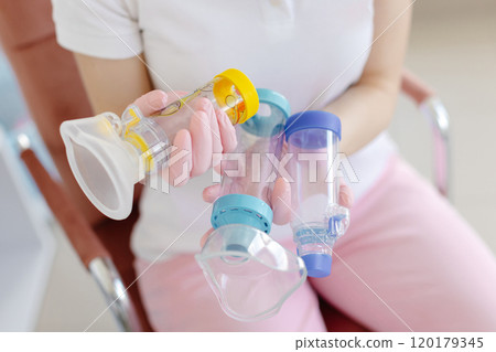 Doctor in pink surgical gloves is holding in hands asthma inhaler aerosol spacer. Inhalation chamber silicone mask for kids treatment respiratory infection Doctor in pink surgical gloves is holding in hands asthma inhaler aerosol spacer. Inhalation chamber silicone mask for kids treatment respiratory infection 120179345