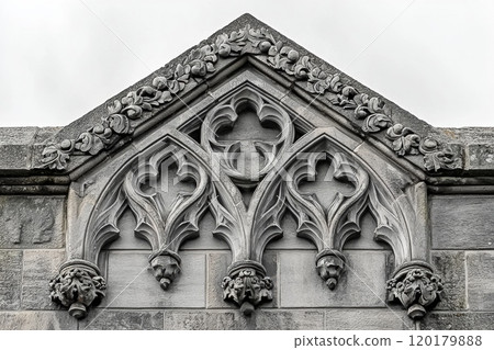 gothic style granite headstone stands majestically arched top displaying intricate stone carvings and sharp motifs clean white background conveying solemn atmosphere. 120179888