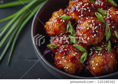 Crispy golden brown Korean fried chicken pieces are glazed sticky spicy sauce beautifully garnished sesame seeds and green onions inviting bold culinary experience. 120180162