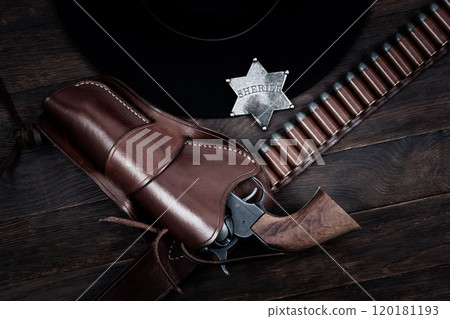 Sheriff star with gun, holster and gun belt with old west hat on table. Top view. Sheriff star with gun, holster and gun belt with old west hat on table. Top view. 120181193