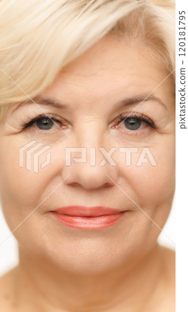 Frontal shot of woman's face, highlighting her blue eyes with long lashes against white studio background. Well-kept, shining skin. 120181795