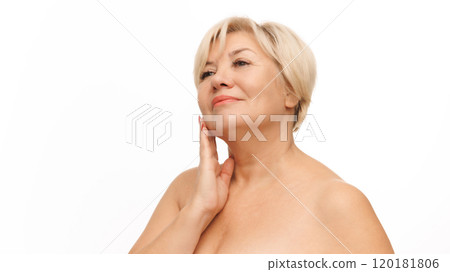 Beautiful, confident 60s woman with bared shoulders touching her soft and smooth skin against white studio background. 120181806