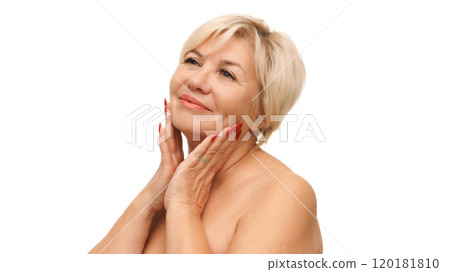 Beautiful Caucasian 60s woman with bared shoulders touching her soft and smooth skin against white studio background. Beautiful Caucasian 60s woman with bared shoulders touching her soft and smooth skin against white studio background. 120181810
