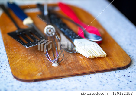 A wooden cutting board with various kitchen utensils on it 120182198