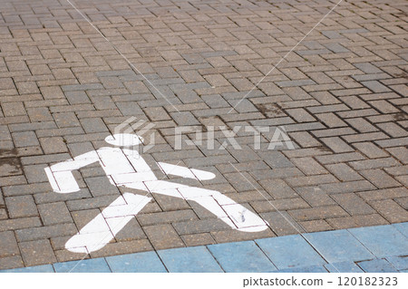 A white pedestrian walk sign is clearly painted on the brick sidewalk 120182323