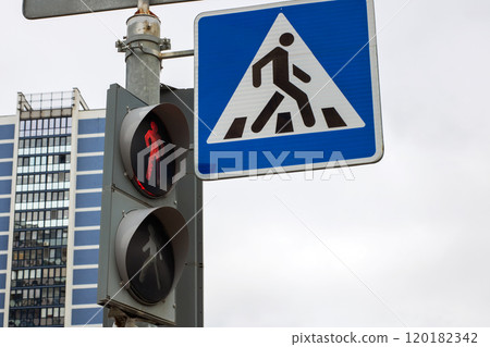 There is a pedestrian crossing sign positioned next to a traffic light 120182342