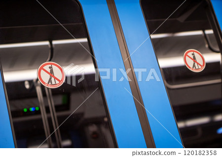 A bright blue train that clearly displays a no standing sign on its door A bright blue train that clearly displays a no standing sign on its door 120182358