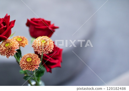 A beautiful vase filled with vibrant red roses and orange flowers 120182486