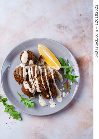 Falafel balls with tahini on gray plate. Israeli cuisine concept. Falafel balls with tahini on gray plate. Israeli cuisine concept. 120182622