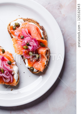 Salmon toast with cream cheese, pickled red onion and capers. 120182643