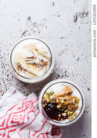 Overnight oatmeal with peanut butter, banana, nuts and jam in jars. 120182668
