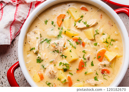 Chicken stew in creamy sauce with potatoes and carrots in red saucepan. Comfort food concept. 120182670
