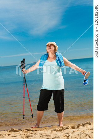 Senior woman practicing nordic walking on beach 120182690