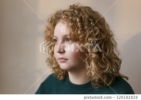 Thoughtful young woman with blonde hair. Portrait of curly hair teenager. Pretty girl looking away. 120182828