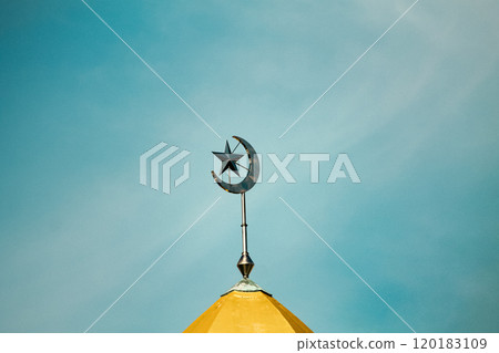 A crescent moon and star, a religious symbol of Islam atop a golden dome of a mosque against a blue sky A crescent moon and star, a religious symbol of Islam atop a golden dome of a mosque against a blue sky 120183109