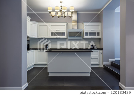 Light kitchen interior with island in suburban home. Stylish kitchen with dark stone countertops. Light kitchen interior with island in suburban home. Stylish kitchen with dark stone countertops. 120183429