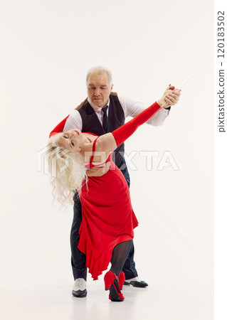 Full-length image of senior couple, man and woman dressed in elegant red dress and black classic suit, dancing tango isolated on white background Full-length image of senior couple, man and woman dressed in elegant red dress and black classic suit, dancing tango isolated on white background 120183502