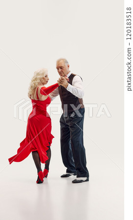 Elderly woman and senior man, elegantly dressed in red dress and black suit, dancing tango with passion isolated on white background Elderly woman and senior man, elegantly dressed in red dress and black suit, dancing tango with passion isolated on white background 120183518